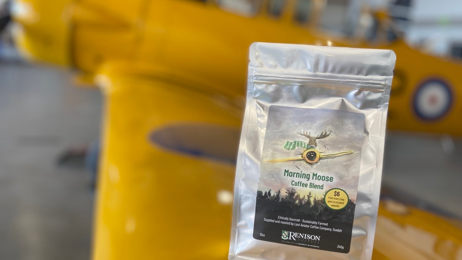 A bag of Renison coffee sitting on the wing of a yellow aircraft