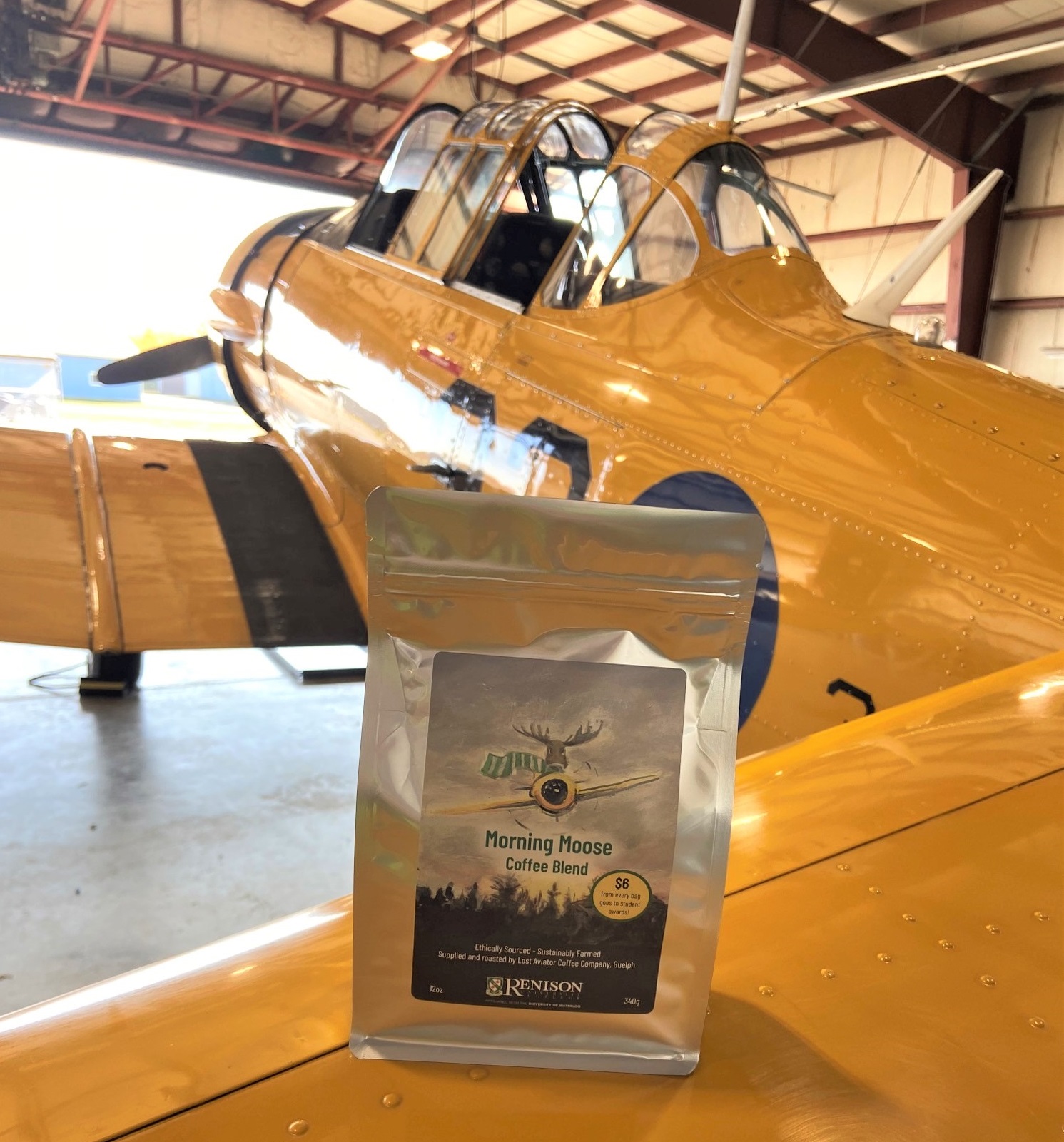 A bag of Renison coffee sitting on the wing of a yellow aircraft